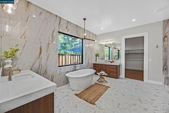 bathroom with tile walls, a bathtub, and vanity