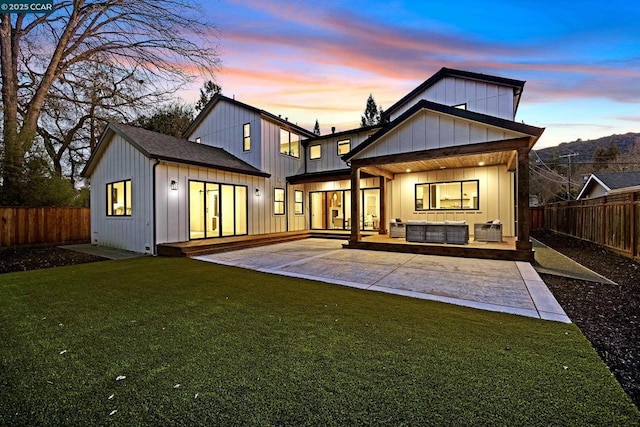 back house at dusk with a yard, outdoor lounge area, and a patio