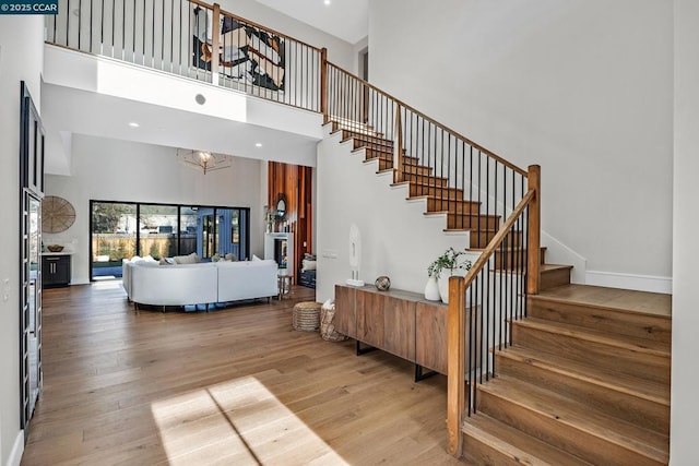 stairs featuring a notable chandelier, hardwood / wood-style floors, and a towering ceiling