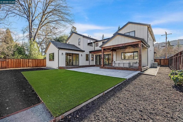 rear view of house with central air condition unit, a patio area, and a yard