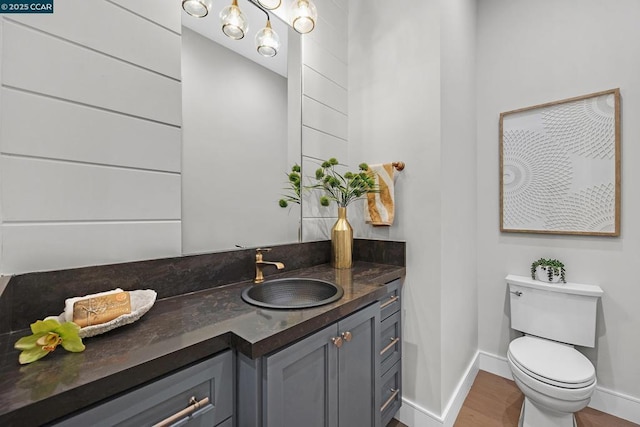 bathroom with toilet, vanity, and hardwood / wood-style floors