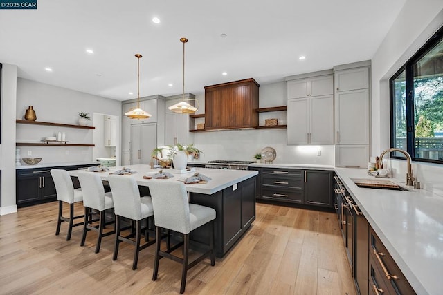 kitchen featuring sink, decorative light fixtures, a kitchen bar, and gray cabinets