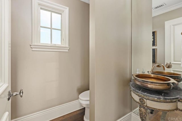 bathroom with toilet, hardwood / wood-style flooring, ornamental molding, and sink