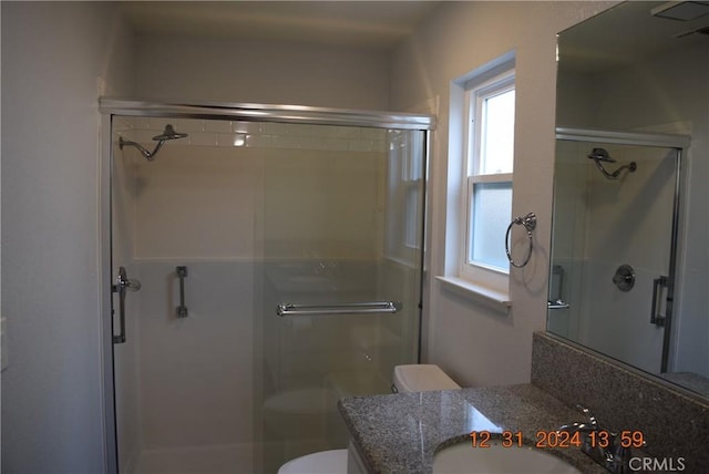 bathroom with toilet, a shower with door, and vanity