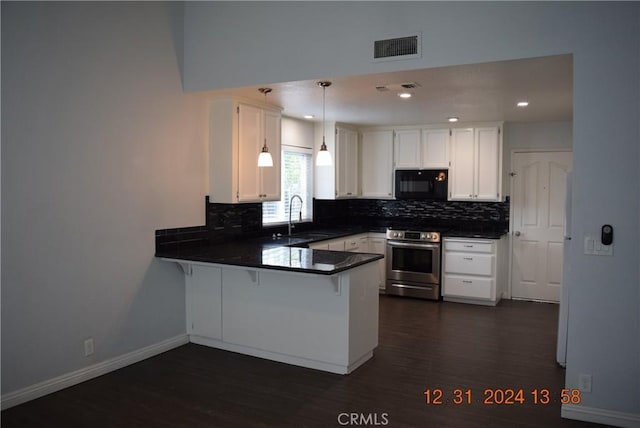 kitchen with kitchen peninsula, pendant lighting, stainless steel range oven, white cabinetry, and sink