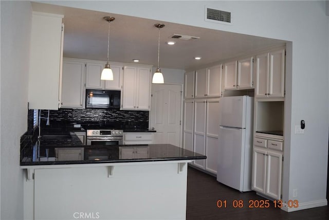 kitchen featuring white cabinets, white refrigerator, a breakfast bar area, and kitchen peninsula