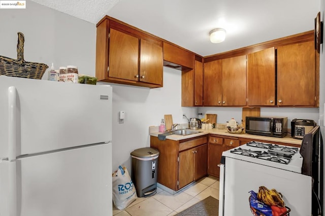 kitchen featuring white appliances, light tile patterned flooring, and sink