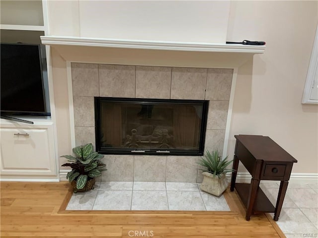 interior details with a tile fireplace and hardwood / wood-style flooring