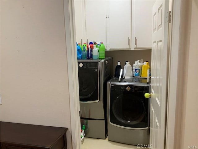 clothes washing area featuring washer and dryer and cabinets