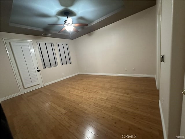 unfurnished bedroom with hardwood / wood-style floors, a raised ceiling, and ceiling fan