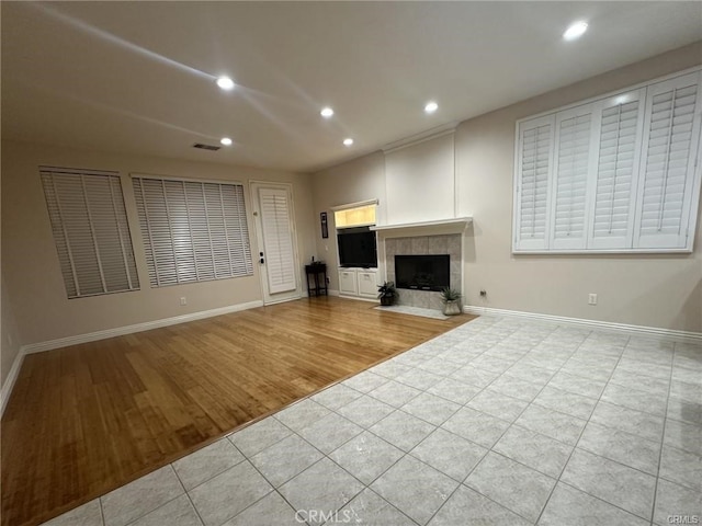 unfurnished living room with a tile fireplace and light tile patterned floors