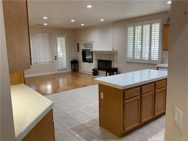 kitchen with light tile patterned floors, a tile fireplace, and tile countertops