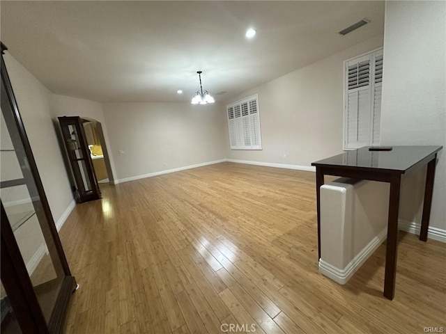 unfurnished living room with light hardwood / wood-style floors and a chandelier