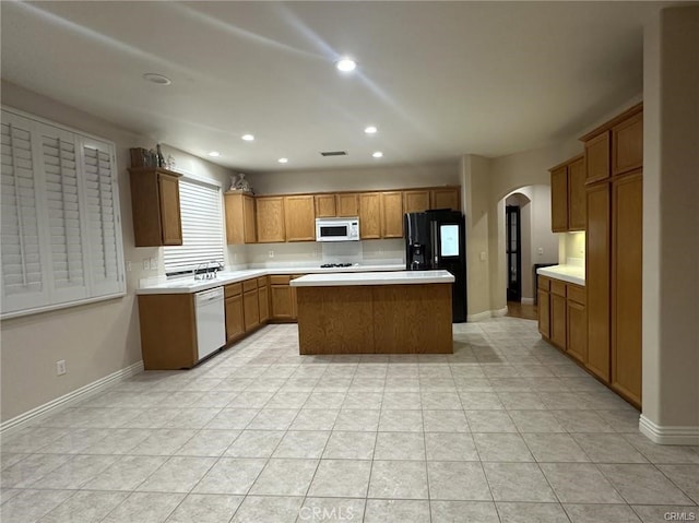 kitchen featuring white appliances, a center island, sink, and light tile patterned floors