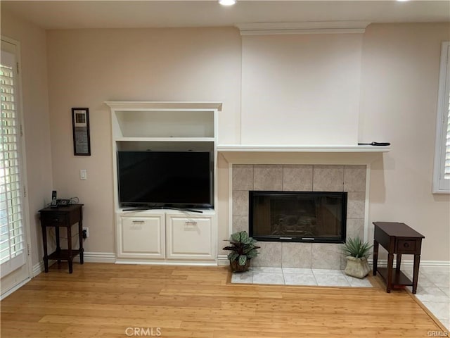 living room with a tiled fireplace and light hardwood / wood-style floors