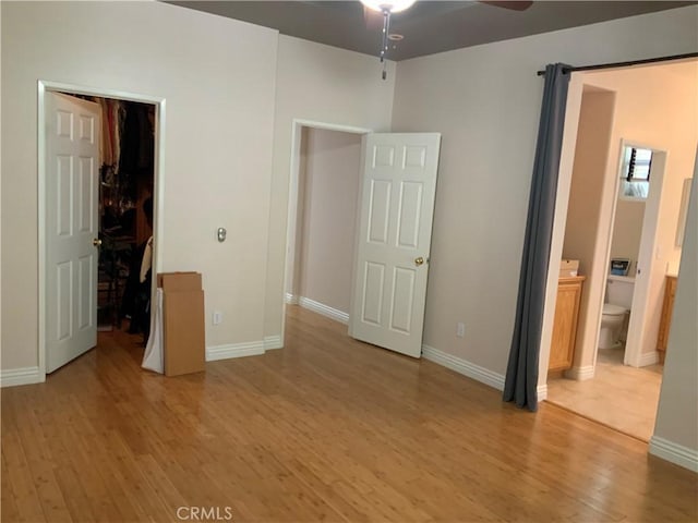 unfurnished bedroom featuring ensuite bathroom, a closet, light hardwood / wood-style flooring, and a spacious closet