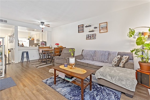 living room featuring ceiling fan and light hardwood / wood-style flooring