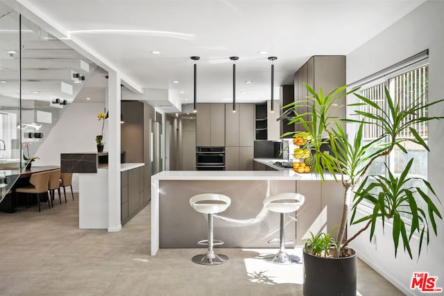 kitchen featuring a breakfast bar, oven, kitchen peninsula, and hanging light fixtures