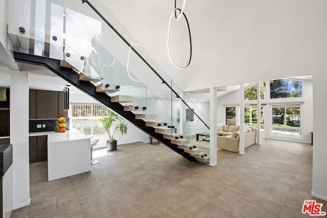 staircase with a high ceiling, concrete floors, and a wealth of natural light