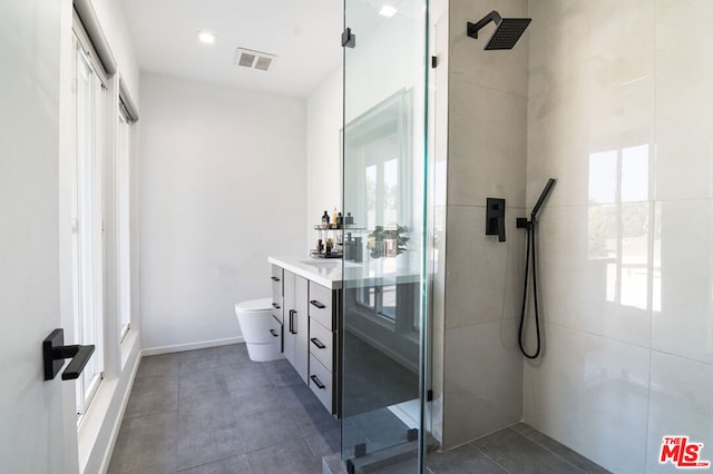 bathroom with vanity, plenty of natural light, a shower with shower door, and toilet