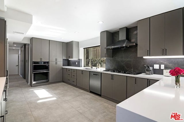 kitchen with wall chimney range hood, gray cabinets, stainless steel appliances, and sink