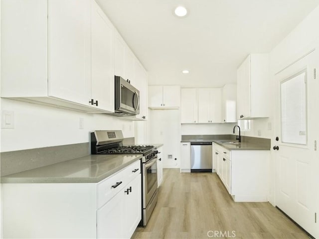 kitchen with white cabinets, stainless steel appliances, light wood-type flooring, and sink