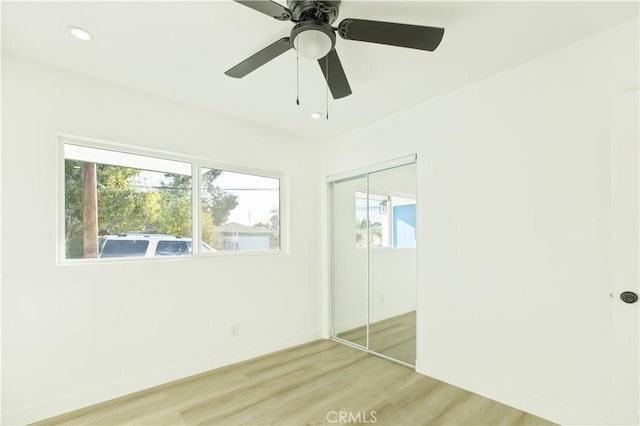 unfurnished bedroom featuring multiple windows, a closet, ceiling fan, and light hardwood / wood-style floors