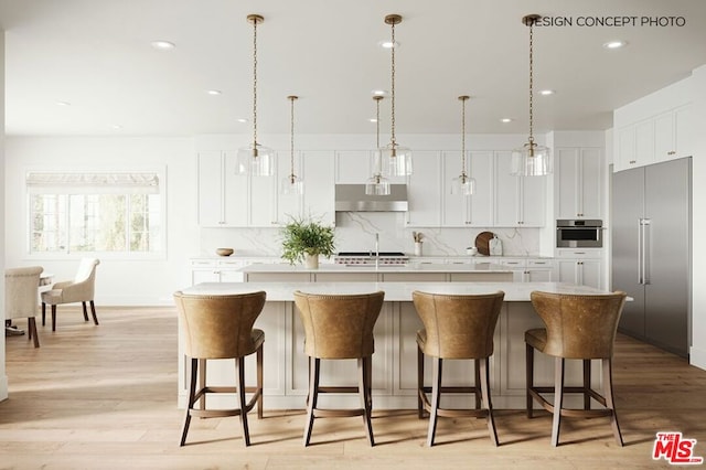 kitchen with appliances with stainless steel finishes, white cabinets, a large island with sink, and decorative light fixtures