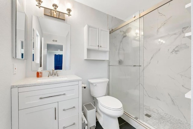 bathroom featuring toilet, a shower with door, and vanity