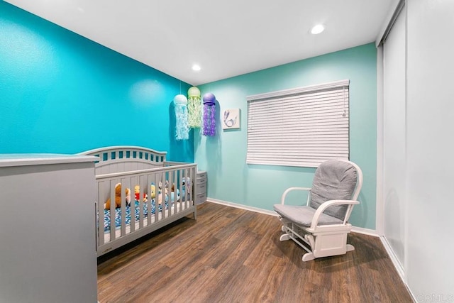 bedroom featuring a nursery area and dark hardwood / wood-style floors