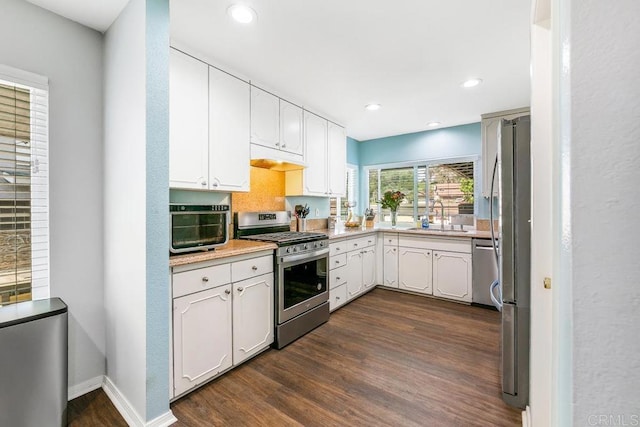 kitchen with dark hardwood / wood-style floors, backsplash, white cabinets, appliances with stainless steel finishes, and sink