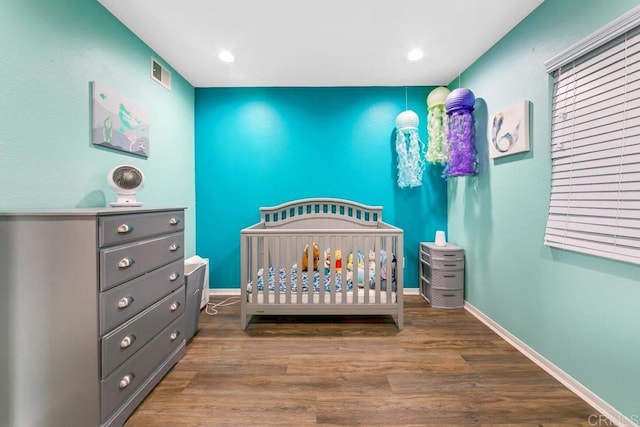 bedroom featuring hardwood / wood-style flooring and a crib