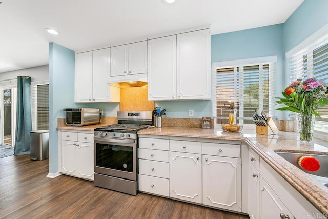 kitchen with dark hardwood / wood-style flooring, white cabinets, plenty of natural light, and stainless steel gas range oven