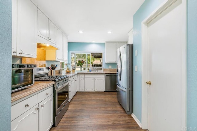 kitchen featuring appliances with stainless steel finishes, dark hardwood / wood-style flooring, sink, white cabinetry, and backsplash