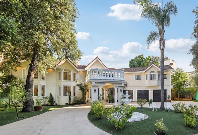 view of front of property with a balcony, a garage, and a front lawn