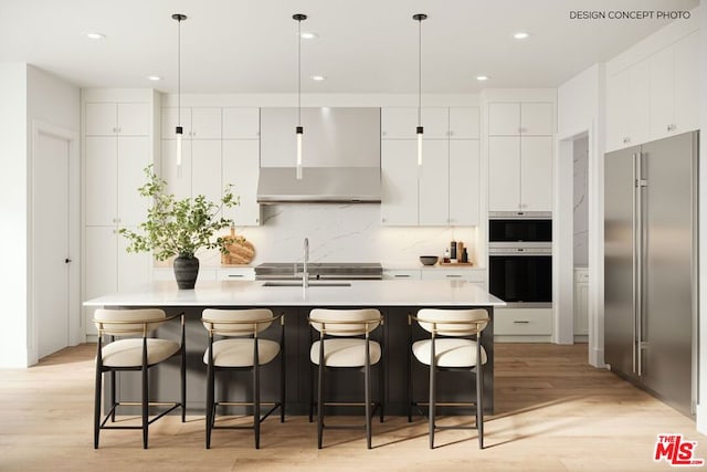 kitchen with hanging light fixtures, an island with sink, light wood-type flooring, sink, and white cabinetry