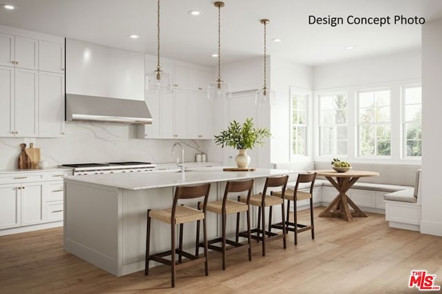 kitchen featuring white cabinetry, decorative light fixtures, and wall chimney exhaust hood