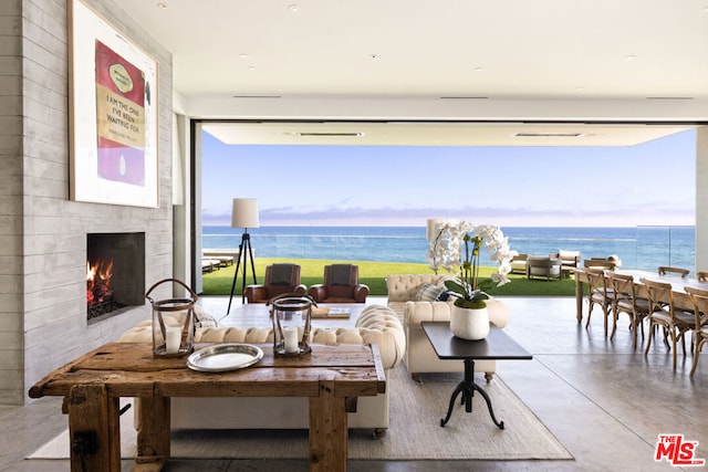 living room with a water view, a tile fireplace, and concrete flooring