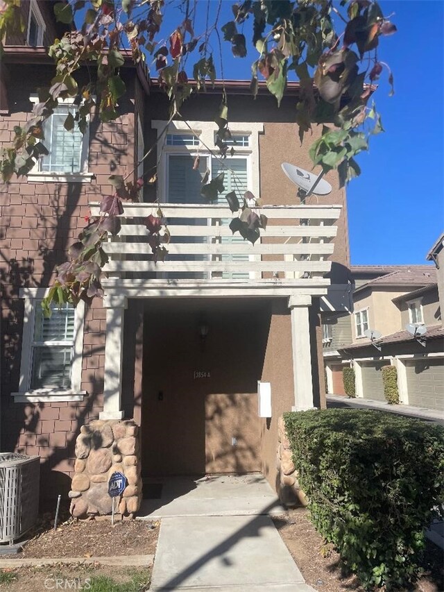 view of front of house featuring a balcony and central air condition unit