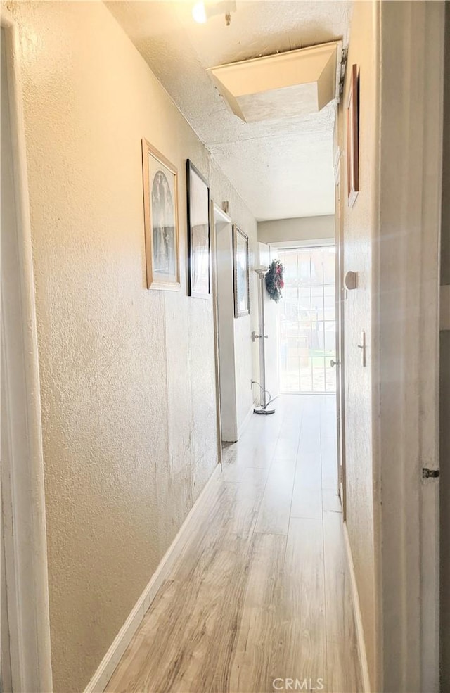 hallway with a textured ceiling and hardwood / wood-style flooring