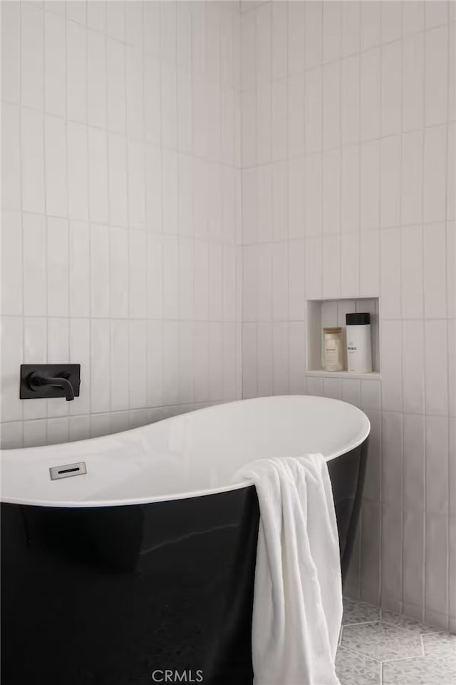 bathroom featuring tile walls, tile patterned flooring, and a bath