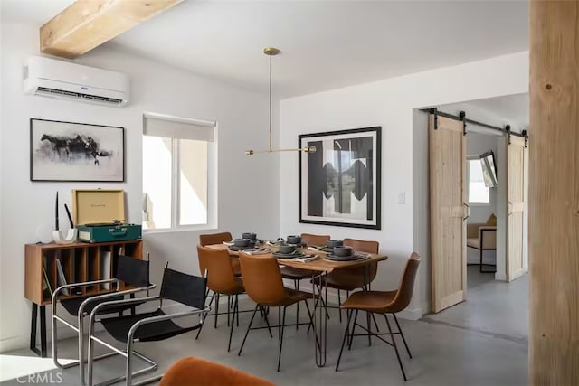 dining area featuring beamed ceiling, concrete floors, a barn door, and a wall mounted AC