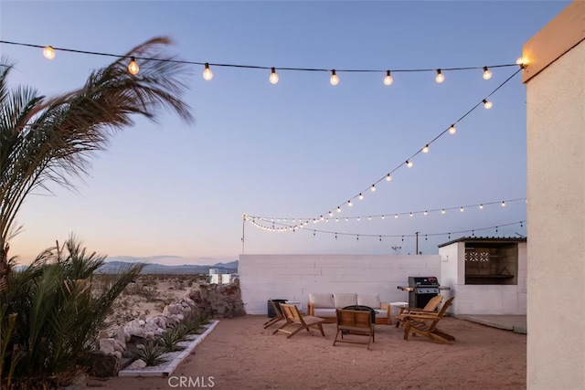 patio terrace at dusk with a grill, an outdoor fire pit, and a mountain view