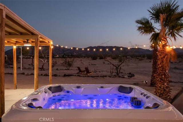 pool at dusk with a hot tub