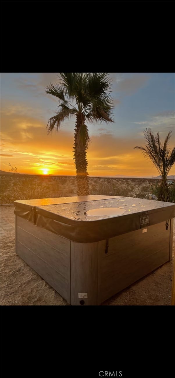 patio terrace at dusk featuring a hot tub