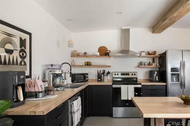 kitchen featuring stainless steel appliances, decorative light fixtures, butcher block countertops, wall chimney range hood, and beam ceiling