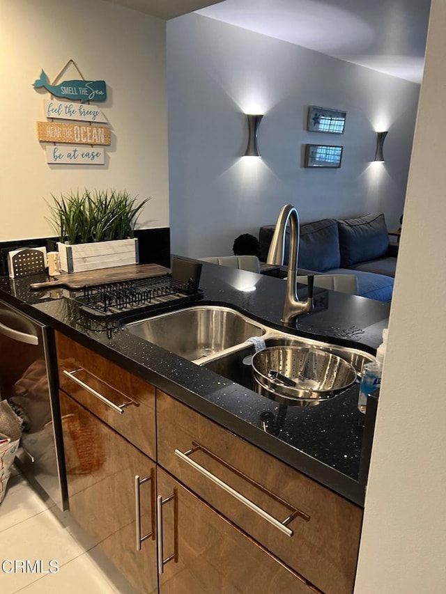 kitchen featuring sink, dark stone countertops, and light tile patterned floors