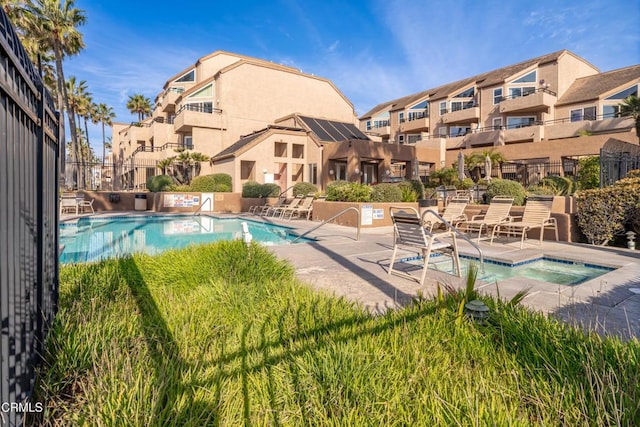 community pool with a patio area and fence