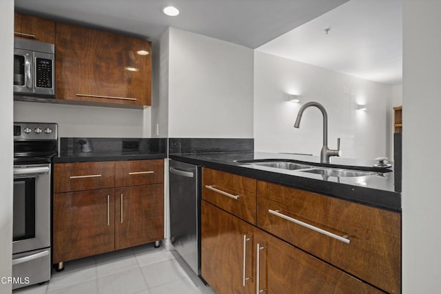 kitchen featuring light tile patterned floors, appliances with stainless steel finishes, dark stone counters, and a sink