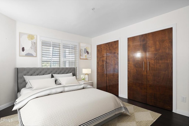 bedroom with baseboards and two closets